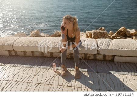 Sports woman engaged in fitness on promenade by sea 89751134