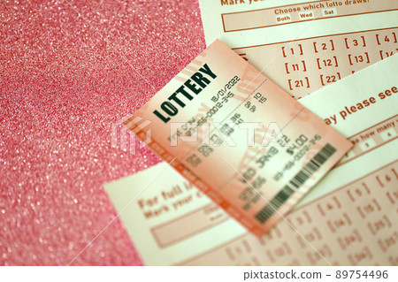 Red lottery ticket lies on pink gambling sheets with numbers for marking to play lottery. Lottery playing concept or gambling addiction. Close up Red lottery ticket lies on pink gambling sheets with numbers for marking to play lottery. Lottery playing concept or gambling addiction. Close up 89754496