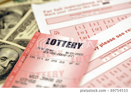 Red lottery ticket lies on pink gambling sheets with numbers for marking on big amount of hundred dollar bills. Lottery playing concept or gambling addiction. Close up Red lottery ticket lies on pink gambling sheets with numbers for marking on big amount of hundred dollar bills. Lottery playing concept or gambling addiction. Close up 89754533