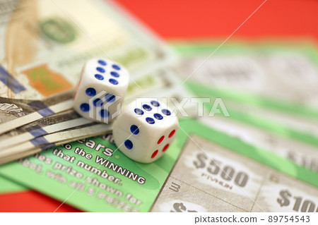 Close up view of green lottery scratch cards with us dollar bills and dice. Many used fake instant lottery tickets with gaming results 89754543