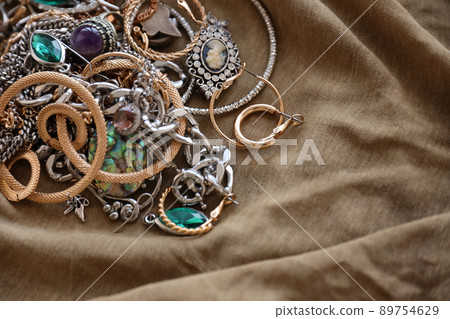 Bunch of stolen jewelry on military uniform cloth fabric. Looting by Russian soldiers in the Ukrainian cities during the Russian attack on Ukraine. Marauders and looters Bunch of stolen jewelry on military uniform cloth fabric. Looting by Russian soldiers in the Ukrainian cities during the Russian attack on Ukraine. Marauders and looters 89754629
