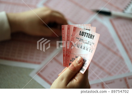 Filling out a lottery ticket. A young woman holds the lottery ticket with complete row of numbers on the lottery blank sheets background. Filling out a lottery ticket. A young woman holds the lottery ticket with complete row of numbers on the lottery blank sheets background. 89754702