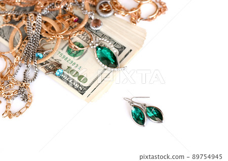 Many expensive golden and silver jewerly rings, earrings and necklaces with big amount of US dollar bills on white background. Pawnshop or jewerly shop Many expensive golden and silver jewerly rings, earrings and necklaces with big amount of US dollar bills on white background. Pawnshop or jewerly shop 89754945