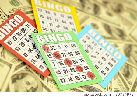 Many bingo boards or playing cards for winning chips and big amount of dollar bills. Classic american or canadian five to five bingo cards on money Many bingo boards or playing cards for winning chips and big amount of dollar bills. Classic american or canadian five to five bingo cards on money 89754972