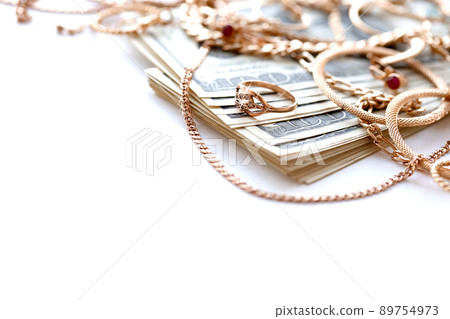 Many expensive golden jewerly rings, earrings and necklaces with big amount of US dollar bills on white background. Pawnshop or jewerly shop Many expensive golden jewerly rings, earrings and necklaces with big amount of US dollar bills on white background. Pawnshop or jewerly shop 89754973