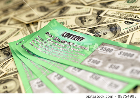 Close up view of green lottery scratch cards and us dollar bills. Many used fake instant lottery tickets with gambling results. Gambling addiction Close up view of green lottery scratch cards and us dollar bills. Many used fake instant lottery tickets with gambling results. Gambling addiction 89754995