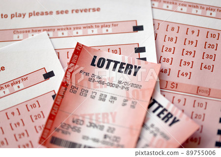 Red lottery ticket lies on pink gambling sheets with numbers for marking to play lottery. Lottery playing concept or gambling addiction. Close up 89755006