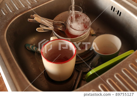 Stack of dirty dishes with food leftovers in the kitchen sink. Unwashed dishes Stack of dirty dishes with food leftovers in the kitchen sink. Unwashed dishes 89755127