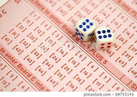 Dice cubes lies on pink gambling sheets with numbers for marking to play lottery. Lottery playing concept or gambling addiction. Close up Dice cubes lies on pink gambling sheets with numbers for marking to play lottery. Lottery playing concept or gambling addiction. Close up 89755143