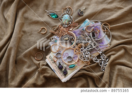 Bunch of stolen jewelry and money on military uniform cloth fabric. Looting by Russian soldiers in the Ukrainian cities during the Russian attack on Ukraine. Marauders and looters Bunch of stolen jewelry and money on military uniform cloth fabric. Looting by Russian soldiers in the Ukrainian cities during the Russian attack on Ukraine. Marauders and looters 89755165