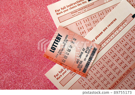 Red lottery ticket lies on pink gambling sheets with numbers for marking to play lottery. Lottery playing concept or gambling addiction. Close up Red lottery ticket lies on pink gambling sheets with numbers for marking to play lottery. Lottery playing concept or gambling addiction. Close up 89755173