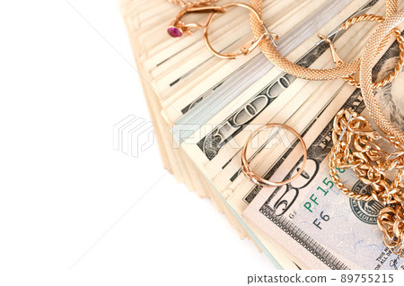 Many expensive golden jewerly rings, earrings and necklaces with big amount of US dollar bills on white background. Pawnshop or jewerly shop 89755215