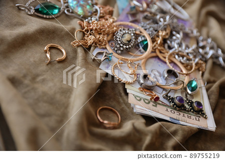 Bunch of stolen jewelry and money on military uniform cloth fabric. Looting by Russian soldiers in the Ukrainian cities during the Russian attack on Ukraine. Marauders and looters 89755219