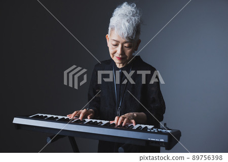 Gray-haired woman playing the keyboard 89756398