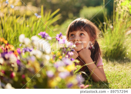 Happy little girl laying on a grass in the garden. Happy little girl laying on a grass in the garden. 89757294