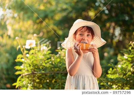 Happy little girl eating corn on the cob. Happy little girl eating corn on the cob. 89757296