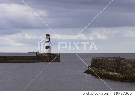 Iconic striped Seaham lighthouse on pier with clouds and sea walls 89757300