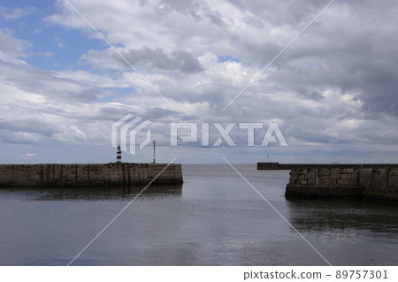 Iconic striped Seaham lighthouse on pier with clouds and sea walls Iconic striped Seaham lighthouse on pier with clouds and sea walls 89757301