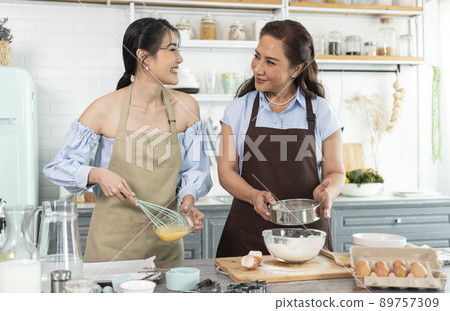 Happy Asian family making preparation dough and bake cookies in kitchen at home. Enjoy family activity together. 89757309