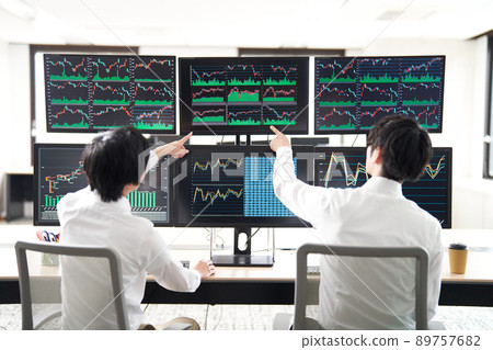 Rear view of a business person pointing at the screen of multiple monitors Trader image Rear view of a business person pointing at the screen of multiple monitors Trader image 89757682