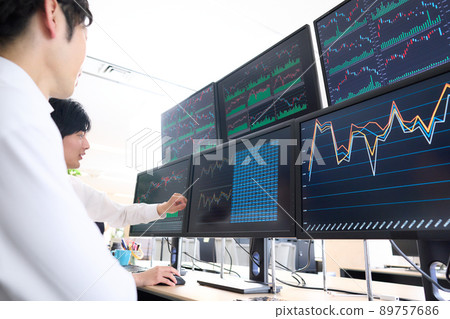 Business person having a conversation while looking at the screen of multiple monitors Business person having a conversation while looking at the screen of multiple monitors 89757686