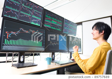 Image of a private investor trader who makes a guts pose while looking at the screen of multiple monitors 89757689