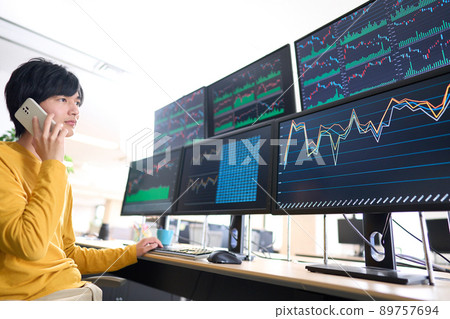 一位私人投資者交易員一邊看著多台顯示器的屏幕一邊用智能手機交談的圖像 89757694