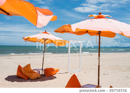 Orange umbrellas and beanbag chairs on white sand beach Orange umbrellas and beanbag chairs on white sand beach 89758556