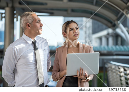 CEO and businesswoman discuss project by laptop in city 89758588