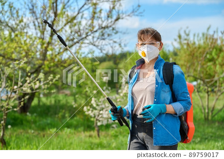 Woman with goggles and respirator with backpack garden spray gun under pressure 89759017