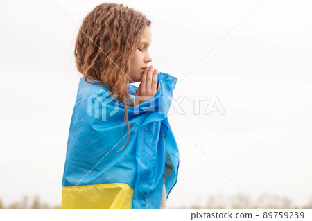 girl with the flag of Ukraine prays for the victory 89759239