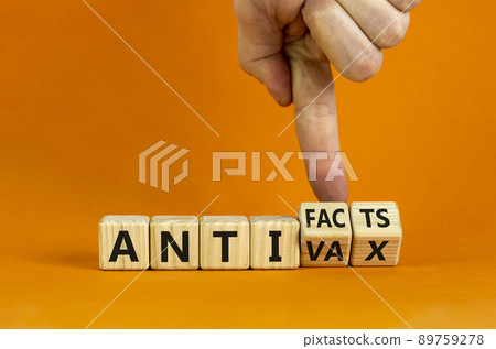 Anti-facts or anti-vax symbol. Doctor turns a cube, changes words 'anti-vax' to 'anti-facts'. Beautiful orange background. Copy space. Business, medical covid-19 anti-facts or anti-vax concept. 89759278