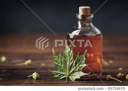 Bottle of maple syrup or healthy tincture and spring maple leaf. 89759659