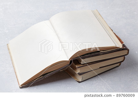 Open vintage book with blank pages lies on a stack of old shabby books Open vintage book with blank pages lies on a stack of old shabby books 89760009