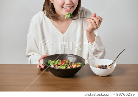 Young vegan woman eating salad and oatmeal 89760259