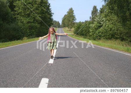 A girl with pink Afro pigtails and dreadlocks walks down the middle of the track with her arms outstretched. The way to the future. Concept. Danger and traffic rules A girl with pink Afro pigtails and dreadlocks walks down the middle of the track with her arms outstretched. The way to the future. Concept. Danger and traffic rules 89760457