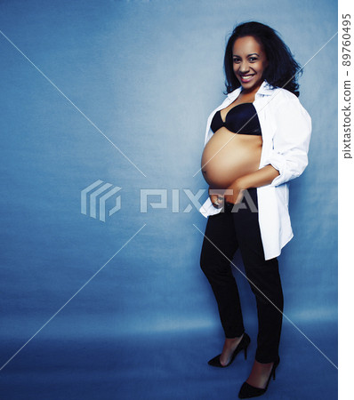 young pretty african american woman pregnant happy smiling, posing on blue background, lifestyle people concept copyspace close up 89760495