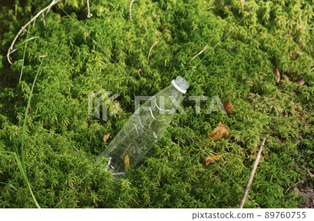 Plastic bottle thrown by a human in the forest lies in the moss. Environmental pollution. Harm to nature and planet caused by humanity. World Environment Protection Day. Recycling of waste and plastic Plastic bottle thrown by a human in the forest lies in the moss. Environmental pollution. Harm to nature and planet caused by humanity. World Environment Protection Day. Recycling of waste and plastic 89760755