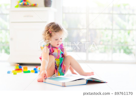 Child reading book in bed. Kids read in bedroom. 89761170
