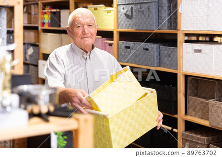 Man pensioner choosing storage basket at store Man pensioner choosing storage basket at store 89763702