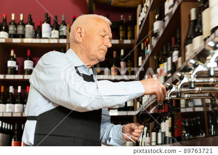 Happy seller pouring wine from wine column 89763721