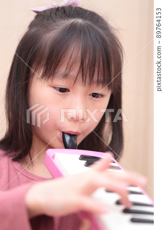 Girl playing keyboard harmonica 89764153