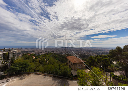 Barcelona, Spain - September 22, 2021: Aerial view over the skyline of Barcelona. Panoramic wide angle view from the summit Mount Tibidabo. Foreground Tibidabo Amusement Park, the sea on the horizon Barcelona, Spain - September 22, 2021: Aerial view over the skyline of Barcelona. Panoramic wide angle view from the summit Mount Tibidabo. Foreground Tibidabo Amusement Park, the sea on the horizon 89765196