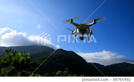 White drone with camera flying in summer mountains White drone with camera flying in summer mountains 89765492