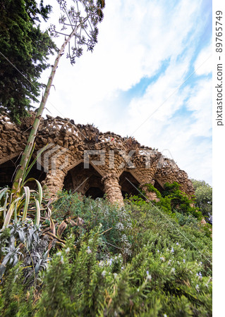 Barcelona, Spain - September 22, 2021: The Parc Guell, located in La Salut at Carmel Hill. The architectural features of the park created by Antoni Gaudi, a renowned architect and the face of Catalan Barcelona, Spain - September 22, 2021: The Parc Guell, located in La Salut at Carmel Hill. The architectural features of the park created by Antoni Gaudi, a renowned architect and the face of Catalan 89765749