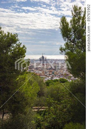 Barcelona, Spain - September 22, 2021: View from Castell de Montjuic over the city to the Sagrada Familia. Cityscape through the trees to the cathedral. Tourist spot of the city. Aerial View Barcelona, Spain - September 22, 2021: View from Castell de Montjuic over the city to the Sagrada Familia. Cityscape through the trees to the cathedral. Tourist spot of the city. Aerial View 89765902