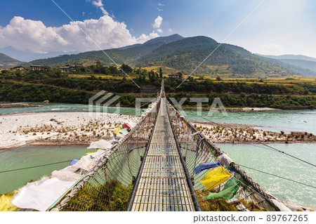 The Punakha Suspension Bridge at the Punakha Dzong. Across the Tsang Chu River to Shengana and Wangkha village. The longest suspension bridge in Bhutan and always decorated with colorful prayer flags. 89767265