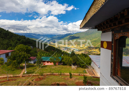 Traditional Bhutanese architecture. Scenic view into a valley in Bhutan . Along the whitewashed traditional house wall. A river meanders through the valley of the mountains, small houses on the slope 89767818