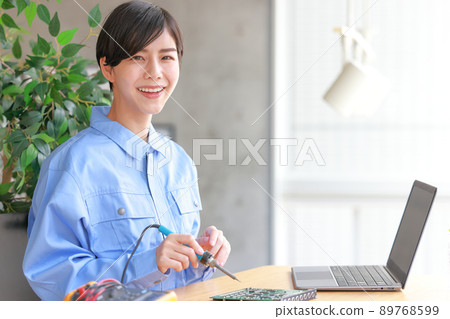 Board maintenance_Smiling woman with a soldering iron 1 89768599