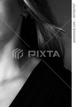 Young tender well-groomed woman's neck in a photo in black and white. Vertical photo. Young tender well-groomed woman's neck in a photo in black and white. Vertical photo. 89768787